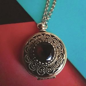 Vintage antique brocade holding locket with amber colored faux stone